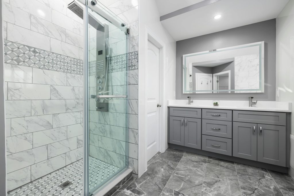 Luxurious modern bathroom featuring grey cabinets and a marble-tiled shower.
